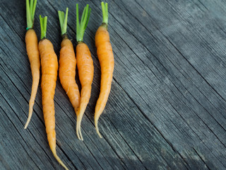 Orange small young carrots on rustic weathered wooden table