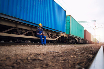 Male worker checking train trailers with shipping containers before departure.
