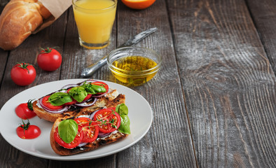 Fresh sandwiches baguette , tomatoes, vegetables and olive oil, ingredients for making a vegan sandwich, close-up. Freshly squeezed orange juice in a glass Dark wooden background, copy space for text