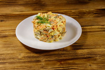 Tasty salad with chicken breast, roasted mushrooms, carrots, grated cheese, eggs and mayonnaise on wooden table