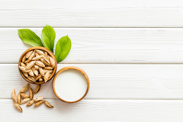 Alternative milk made from almond. Drink near unpeeled on white wooden table top-down copy space