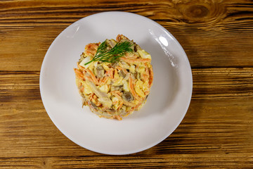 Tasty salad with chicken breast, roasted mushrooms, carrots, grated cheese, eggs and mayonnaise on wooden table. Top view