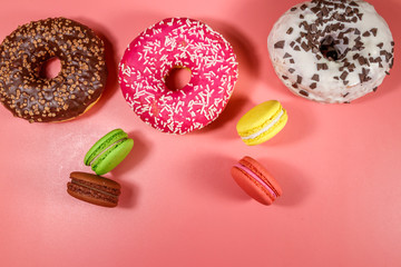 Tasty donuts and macaroons on pink background. Top view