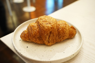 Close up ceramic plate of butter plain croissant