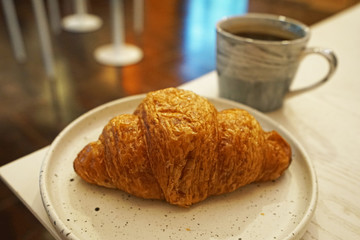 Close up plain butter croissant served with a cup of hot black coffee
