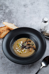 Porcini mushrooms cream soup with toasts, served on stone background with copy space