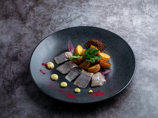 Gourmet atlantic salted herring with baked baby potato on stone grey background