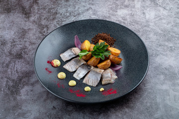 Gourmet atlantic salted herring with baked baby potato on stone grey background
