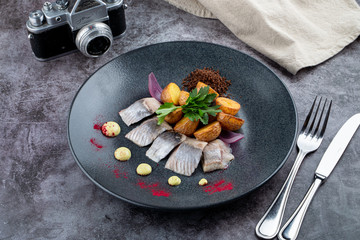 Gourmet atlantic salted herring with baked baby potato on stone grey background