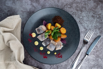 Gourmet atlantic salted herring with baked baby potato on stone grey background