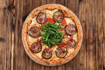 Italian pizza with grilled eggplant, arugula, tomatoes, parma ham and sirtaki cheese