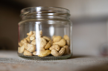 Cashew nuts in a jar which standing on a white vintage table with a kitchen on background. Cashew nut is a healthy vegetarian protein nutritious food.