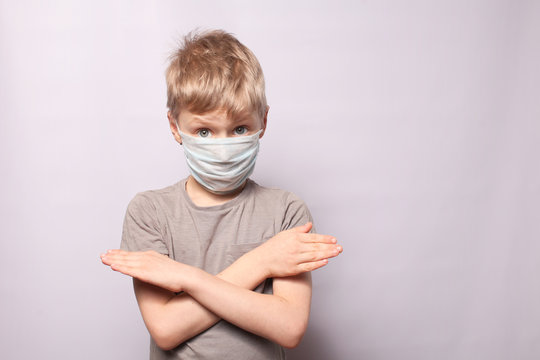 Little Boy Shows Gesture No. Face Of A Boy Wearing A Mask With Fear In His Eye On A Gray Background. The Concept Of Coronavirus And Air Pollution Pm2.5. COVID-19