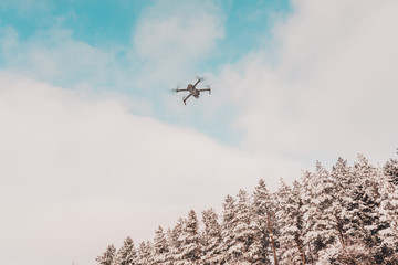 The drone flies in the winter above the forest and shoots landscape videos.