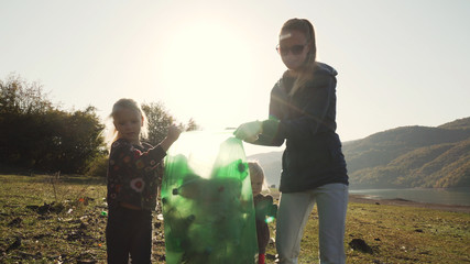Young mother and her daughters carry a green bag full of trash counter light
