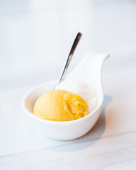 Mango and coconut ice cream served on mini white bowl
