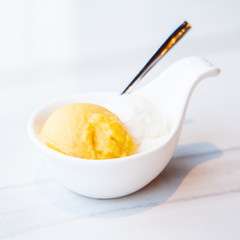 Mango and coconut ice cream served on mini white bowl