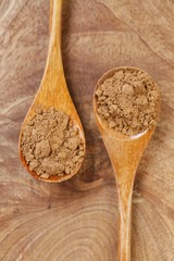  guarana powder in wooden spoons on a wooden board on a black background.