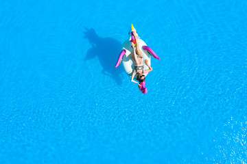 Top view of the pool with a girl in a swimsuit on an inflatable circle. Relaxing and tanning in the summer.