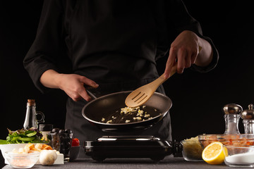 Cooking a fresh salad with shrimp, fries honesty in a pan. On a black background for design. Seafood, Oriental and Thai cuisine.