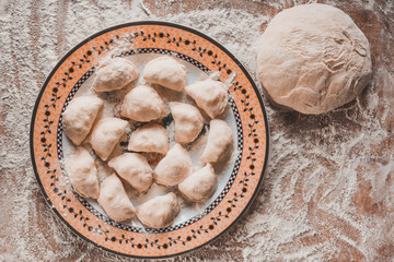 Raw dumplings are laid on a prepared plate for further preparation.2020