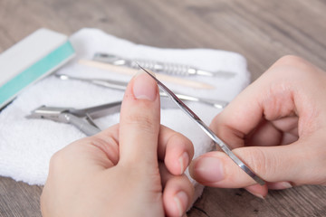 A woman cuts long nails on her hands. Manicure, cuticle, wound, scratch, injure. Hand care, home manicure. Nail salon, Spa, beauty.