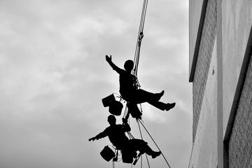 Two professional men insulate a residential building outside. Industrial alpinism.