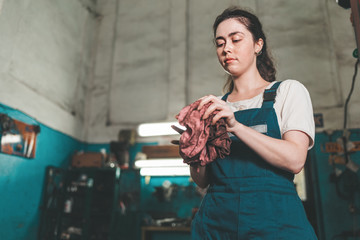 Gender equality. Portrait of a young woman in uniform, working in a workshop, which wipes his hands with a rag. Bottom view. Auto shop in the background