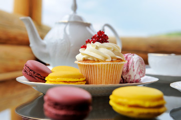 Composition with bright pastries on a saucer and teapot.