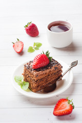 Truffle cake with chocolate and strawberries and mint on a white wooden table. Selective focus.