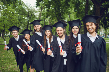 A group of graduates with scrolls in their hands are smiling