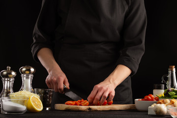 Chef slices cherry tomatoes to make shrimp marinade sauce. Seafood and oriental recipes.