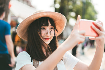 Young asian influence girl traveling in bangkok with smartphone for upload to social network.