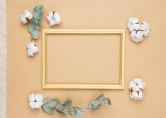 Eucalyptus leaves and cotton flowers on pastel beige background. Flat lay, top view. Copy space.