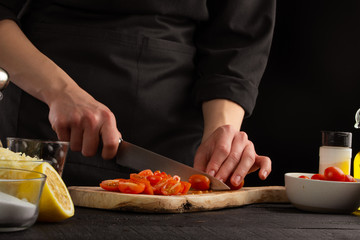 Chef slices cherry tomatoes to make shrimp marinade sauce. Seafood and oriental recipes.