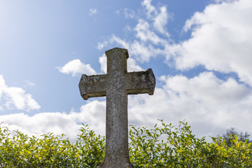 grey grave stone cross standing alone in Cemetery, blue sky background, daylight, rip concept