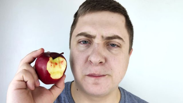 A man bit an apple and blood came out of his gums. Gum bleeding, symptoms of gingivitis, periodontitis and periodontal disease.
