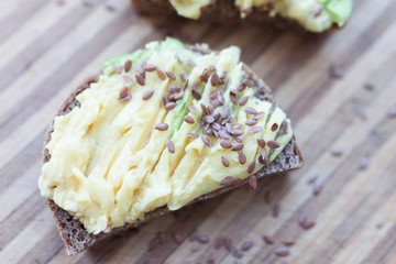 whole grain toast with avocado and flax seeds on a wooden board