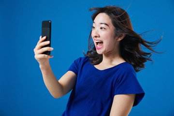 スマートフォンを持って驚く女性