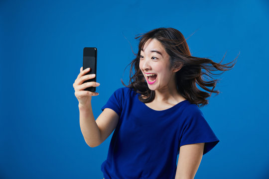 スマートフォンを持って驚く女性