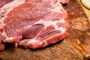 a raw meat, pork neck on a wooden background