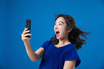 スマートフォンを持って驚く女性