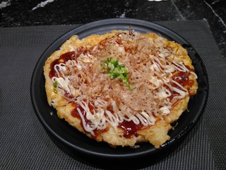 Japanese pizza on a dark plate on a black table