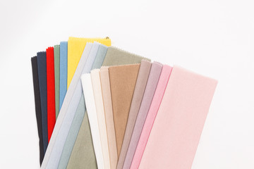 Multicolored fabrics folded in a stack top view on a white background. Multi-colored textile