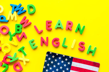 Learn English text near American flag and letters on yellow background top-down