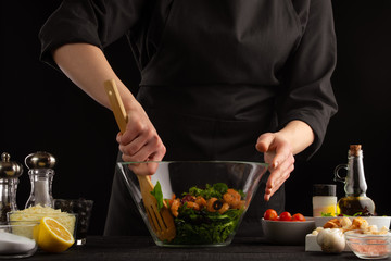 Chef cooks a salad, mixed on a black background. Cooking and home recipes.