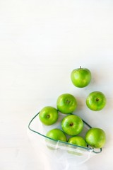 Reusable eco-friendly bag with green apples on a white wooden background. Sustainable lifestyle concept, zero waste shopping, ecological. Top view, flat lay, copy space.