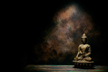 Statuette of Buddha on a dark background.