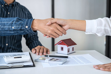 Real estate agent and customers shaking hands together celebrating finished contract after signing...