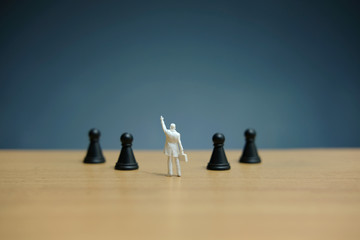 Business strategy conceptual photo - Miniature businessman pointing upside in the middle of chess piece on a chessboard